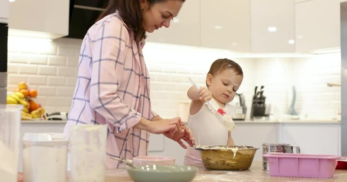 mom and little child girl mix the dough for muffins in the kitchen, bake cookies. happy time together