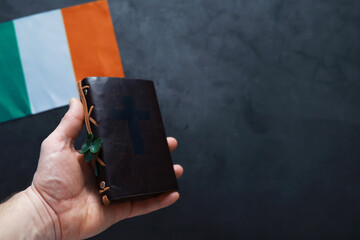 A leather-bound Bible on the table. Religious Christian Irish celebration. Four-leaf clover symbol...