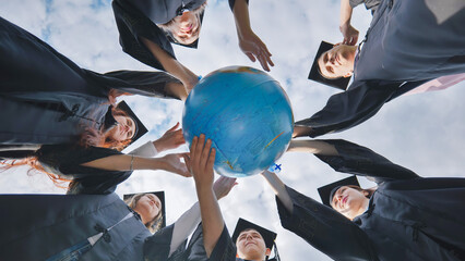 Graduating students twirl a geographic globe of the world in their hands.