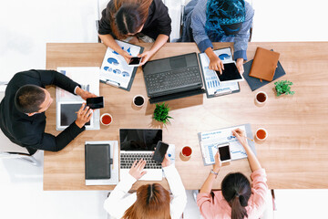 Top view of businessman executive in group meeting with other businessmen and businesswomen in modern office with laptop computer, coffee and document on table. People corporate business team uds
