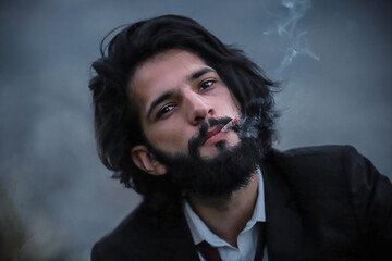 Close up Man with Long Hairs, Wearing Suit, Smoking a Cigarette While Looking at the camera