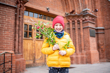 boy holding willow branches goes to church. happy schoolboy celebrating verbal or palm sunday