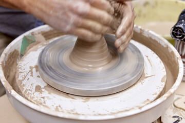 Fototapeta premium male hands making ceramic cup on pottery wheel, Close-up