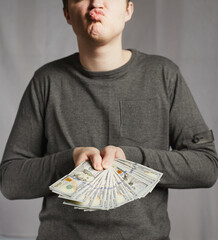 A young man is happy with the money he has received, which he is holding in his hands. Big win,...
