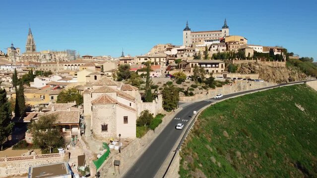 Toledo, Spain: Aerial drone footage of cars driving on a road by the famous Toledo old town with the Cathedral and the Alcazar castle in the Castilla-La Mancha in central Spain. 