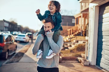 Fotobehang Happy child playing with father in sunny suburban street © Geber86