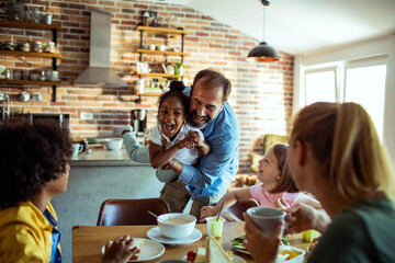 Happy diverse family enjoying breakfast together at home