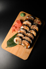 Top view of sushi rolls covered in brown sauce and sprinkled with sesame seeds with cucumber and fish filling