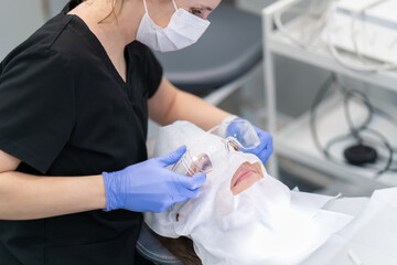 A dentist puts on protective glasses for the patient to provide dental services. Preparing the patient for the procedure of brushing and polishing teeth, removing tartar and oral hygiene.