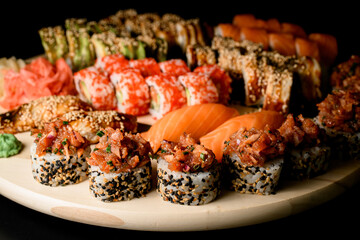 Side view of set of sushi rolls, focus on rolls sprinkled with black and white sesame seeds with fish filling