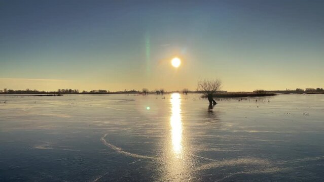Ice skating point of view on the floodplains of the Zwarte Water near Hasselt in nature  during a cold winter sunset in The Netherlands.