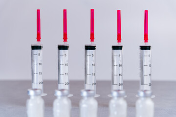 Composition as medical material composed of a line of syringes in the background perfectly aligned with blurred foreground of antibiotic bottles