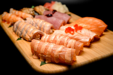 Side view of nigiri set, focus on foreground nigiri with orange sauce