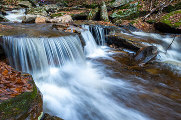 Fototapeta na wymiar Cascade of waterfalls in a mountain gorge, fast flowing water, long exposure