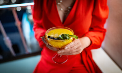 Woman in red dress drinking mango daiquiri cocktail.