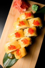 Top view of sushi rolls covered with yellow sauce and decorated with red caviar on top close up