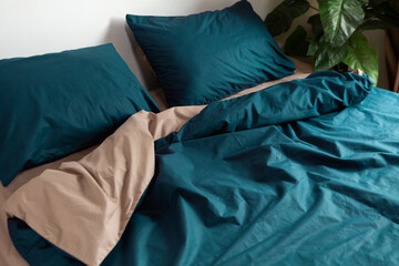 Cotton bed linen of two colors on the bed, pillow and blanket