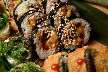 Close-up of sushi rolls covered in sauce and sprinkled with sesame seeds