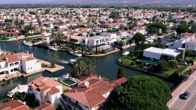 Cinematic drone shot of luxurious private community in Empuriabrava. Tourist boat navigate through waterway canals with excursion. Summer family activity. Real estate property for sale. 