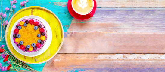 Kaffee und Kuchen auf einem Holztisch angerichtet in bunten Farben 