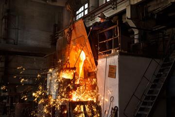 Industrial worker oversees molten metal pouring in foundry. Steelworker in protective gear at metal manufacture. Heavy industry scene with fiery sparks, furnace heat in steel mill.