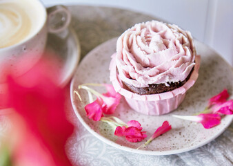 Aesthetic pink cupcake with cup of coffee. Flowers decoration. Escapism dreamy desserts. Holiday background