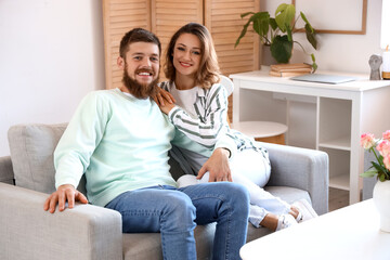 Happy couple in love sitting on sofa at home