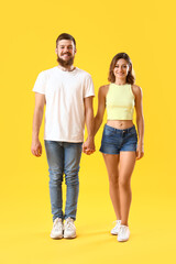 Obraz premium Happy couple in love holding hands on yellow background