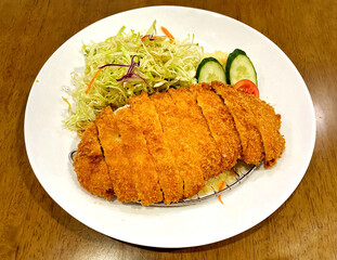 Japanese Pork Cutlet recipe is known as Tonkatsu in Japan. The delicious, deep-fried pork cutlet served on a white plate with salad in the restaurant.