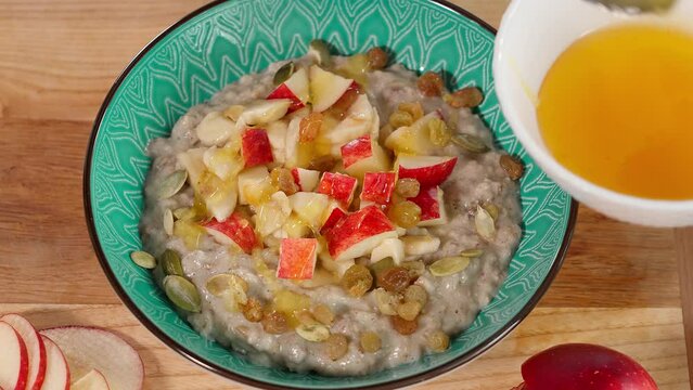Oatmeal porridge, drizzled with honey, served with apples, bananas, ium, sunflower and pumpkin seeds. Healthy breakfast, clean eating, diet concept