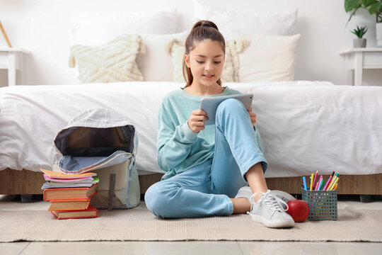 Little schoolgirl using tablet computer in bedroom