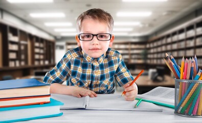 Pensive smart child taking notes, in modern classroom.