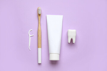 Toothbrush, toothpaste, floss toothpick and tooth model on lilac background. World Dentist Day
