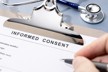 Hand filling a Informed Consent form on desk