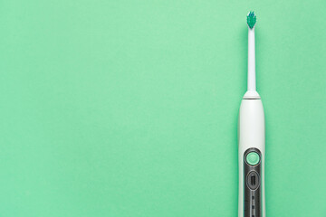 Modern electric toothbrush on green background. World Dentist Day