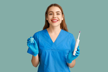 Female dentist with tooth model and electric toothbrush on blue background. World Dentist Day