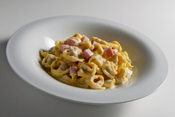 Soup bowl with tortellini pasta with cream and ham