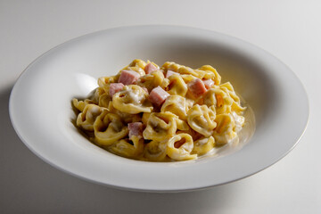 Soup bowl with tortellini pasta with cream and ham