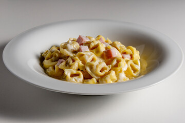 Soup bowl with tortellini pasta with cream and ham
