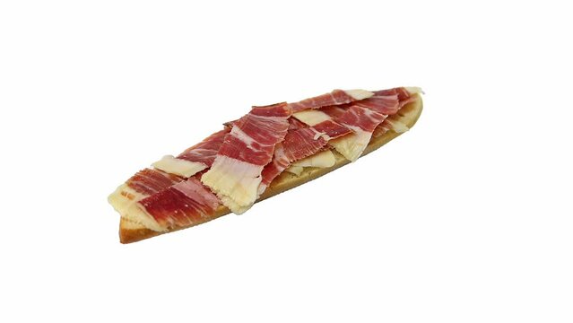 Sliced Iberian ham (jam&oacute;n serrano) on a slice of bread, rotating, isolated on white background.