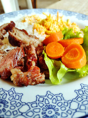 Closeup of colorful vegetables and barbecue on Brazilian meal known as Prato Feito on the decorated plate.