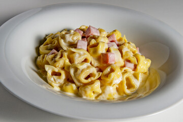 Soup bowl with tortellini pasta with cream and ham