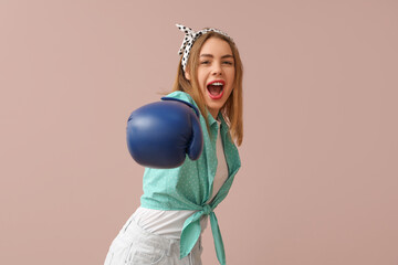 Happy young pin-up woman with boxing glove on pink background