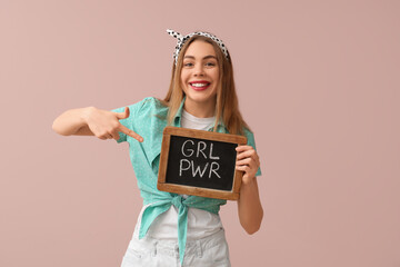 Happy young pin-up woman pointing at chalkboard with text GIRL POWER on pink background