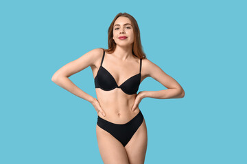 Naklejka premium Attractive young woman in black underwear on blue background