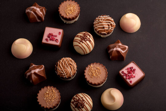 photo featuring assorted chocolates—a sweet gift with different flavors. This calorie-worthy selection, rich in cocoa, promises a delectable dessert experience.