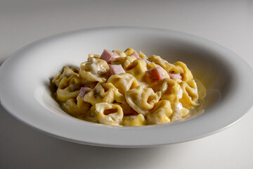 Soup bowl with tortellini pasta with cream and ham