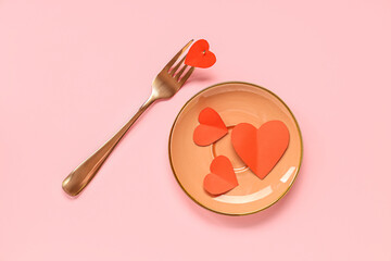 Composition with paper hearts, plate and fork on pink background. Valentine's day celebration