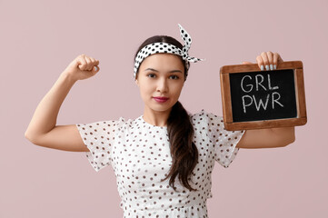 Beautiful young Asian pin-up woman holding chalkboard with text GIRL POWER and showing her muscles...
