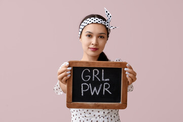 Beautiful young Asian pin-up woman holding chalkboard with text GIRL POWER on pink background